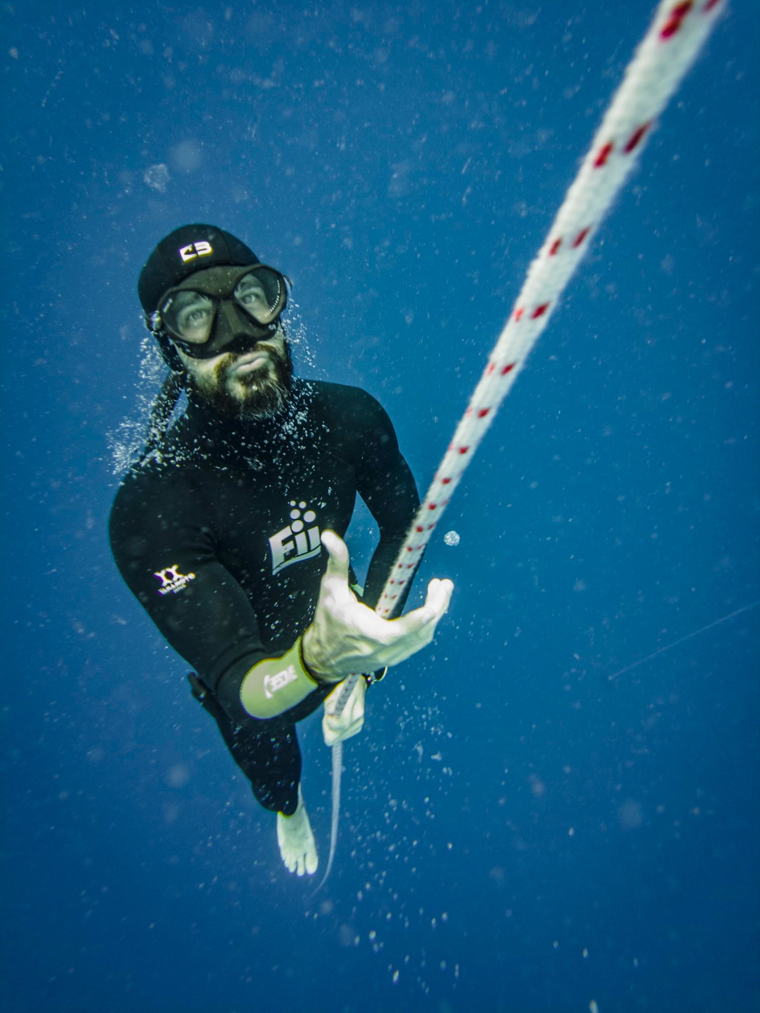 Costa pulling up the dive line on one breath, trailing bubbles