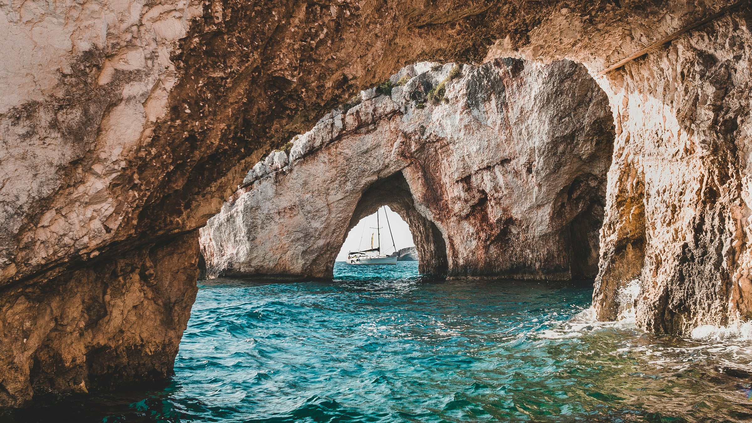 A sailboat seen through a sea cave arch
